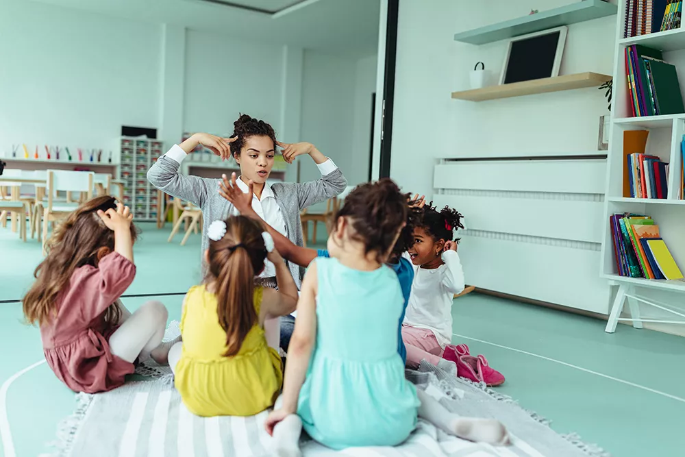 Teacher is playing with cheerful children at preschool in maryland