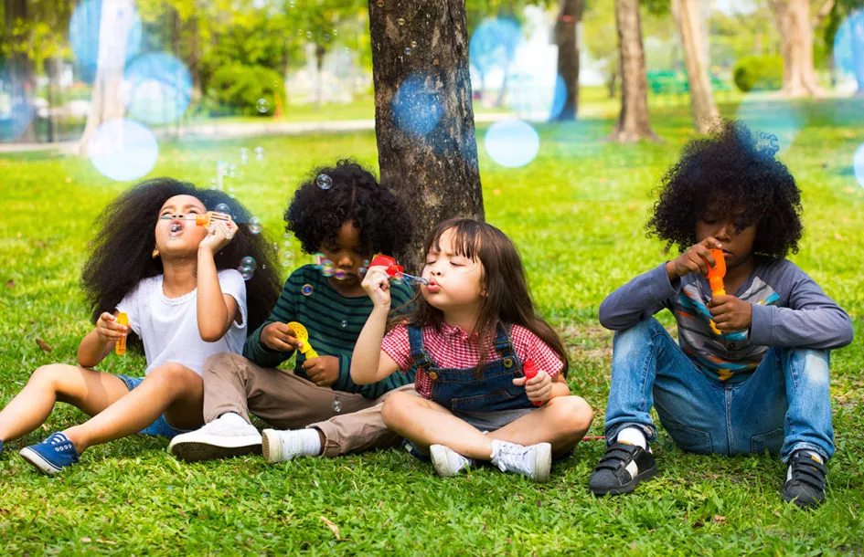 Group of kids playing outside and blowing bubbles in the summer.
