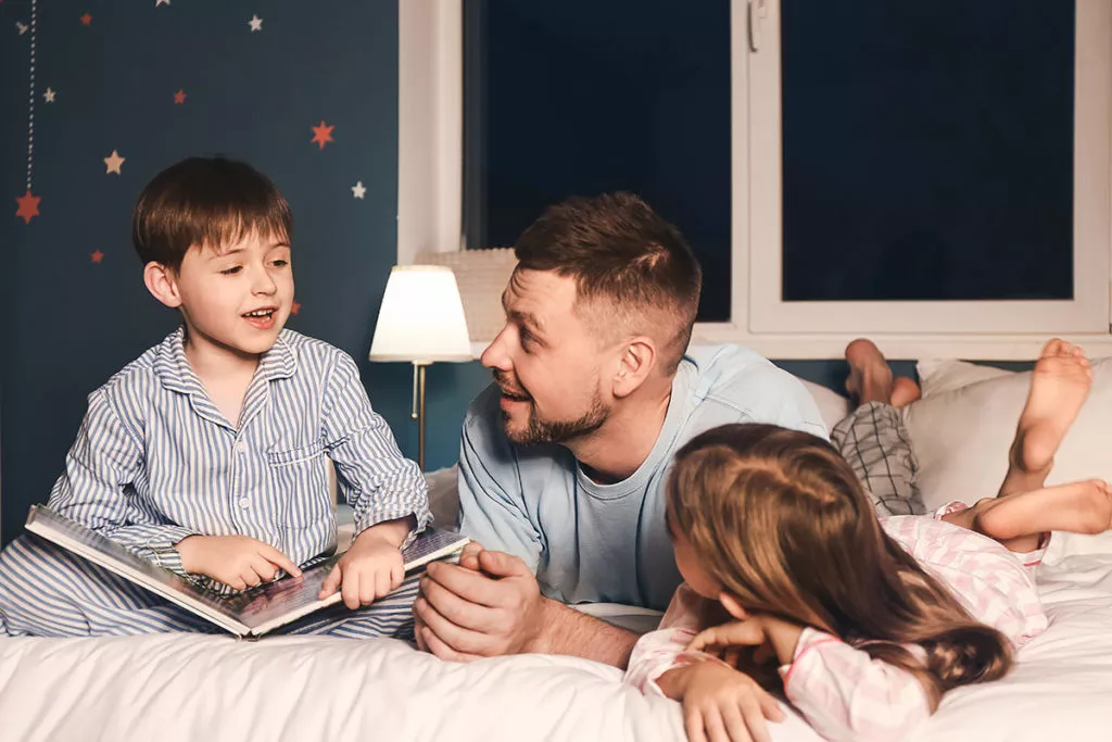 Father and his little children reading bedtime story at home