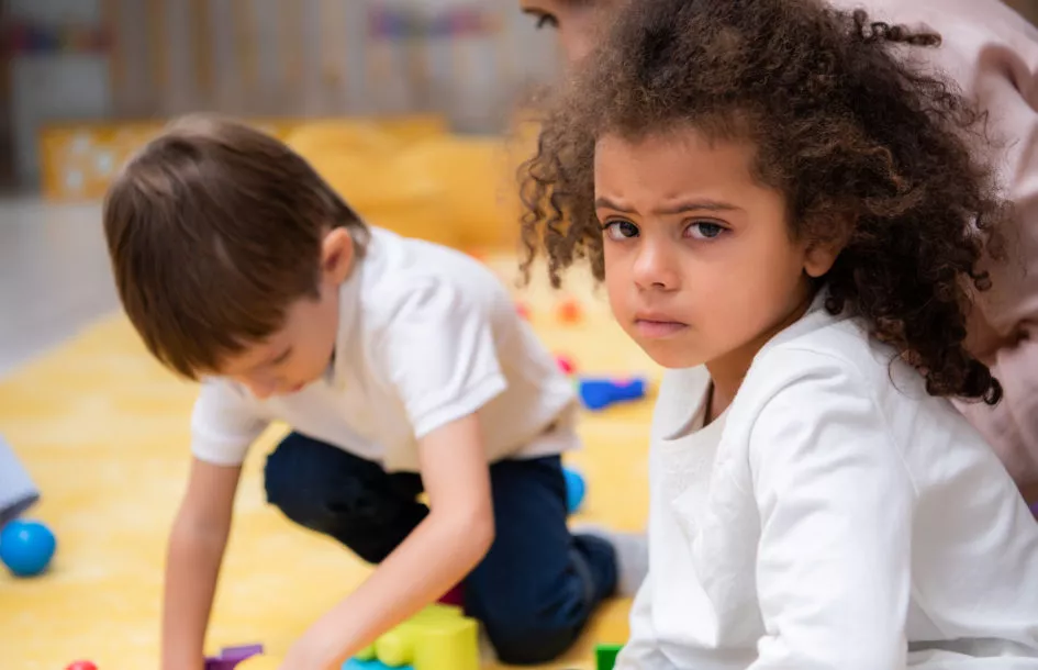 upset african american kid looking at camera in kindergarten