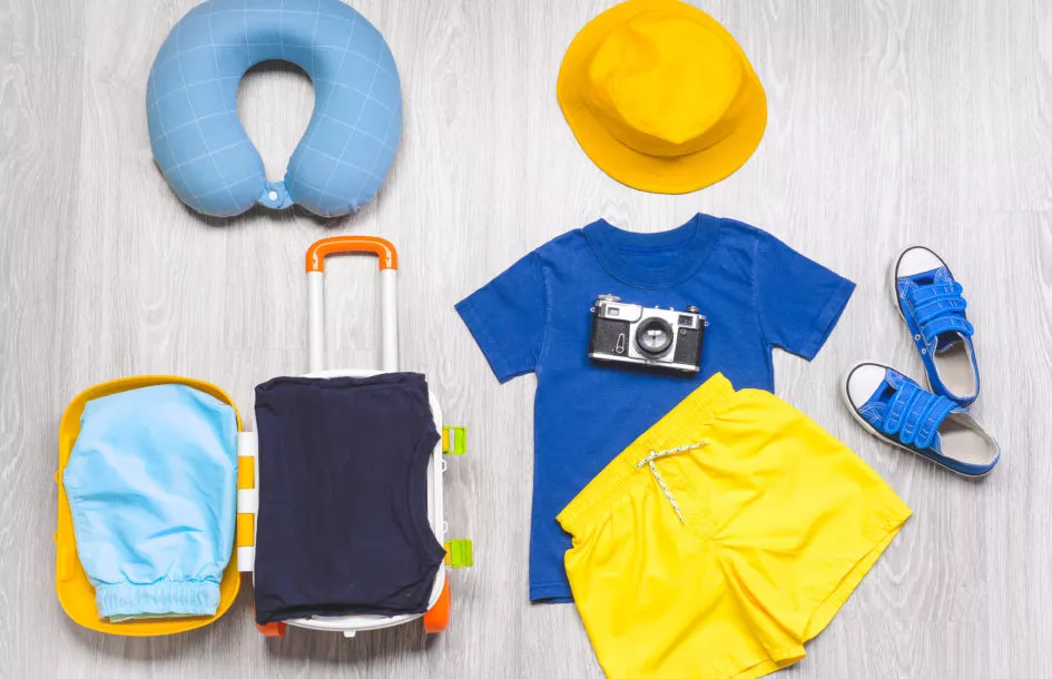 Suitcase with travel accessories for children on wooden background