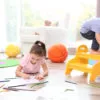 Little girl drawing and boy playing at home