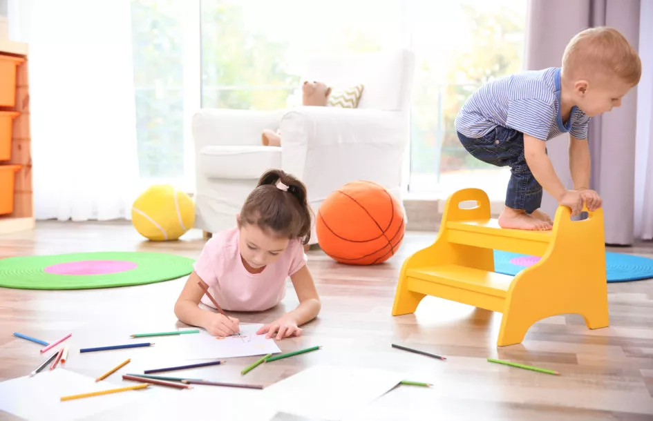 Little girl drawing and boy playing at home