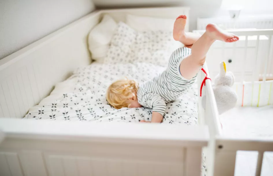 Little toddler boy getting out of a cot. Domestic accident. Dangerous situation at home.