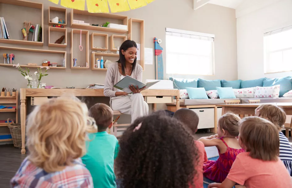 Early literacy in preschool: Teacher At Montessori School Reading To Children At Story Time