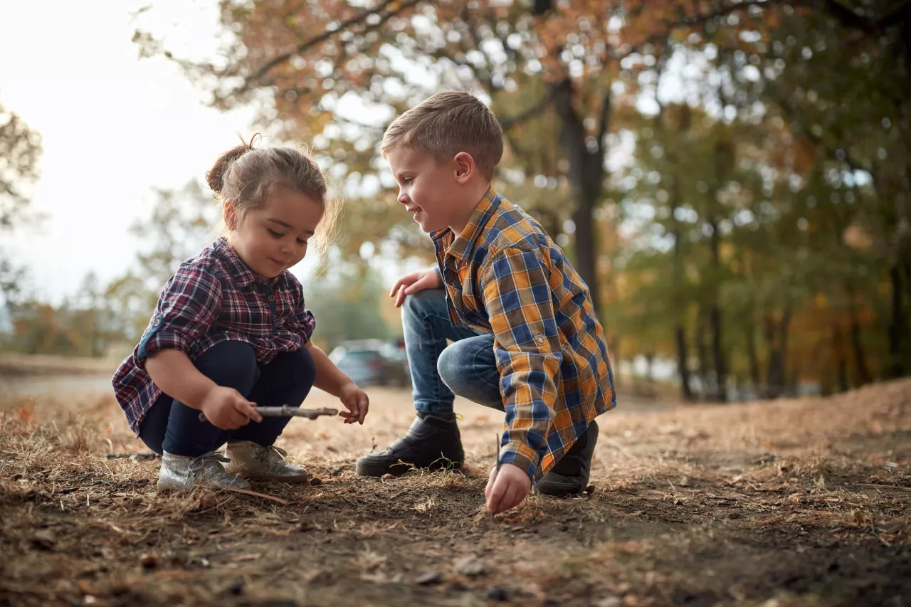 Fun fall nature walk activities for kids:mPreschool brother and sister playing with sticks in nature.