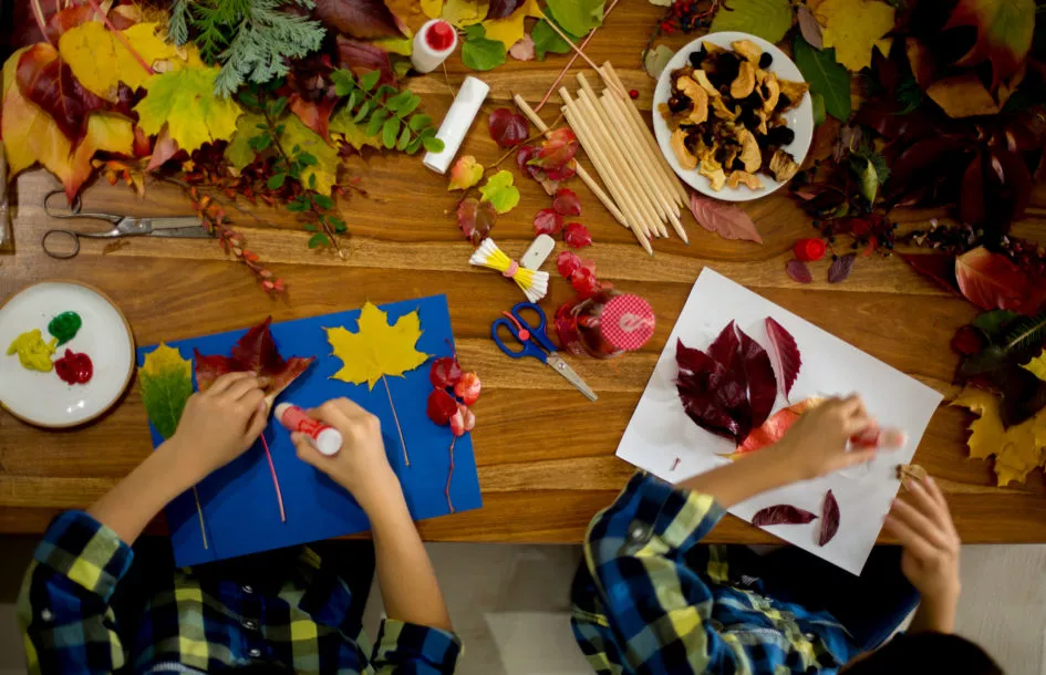 Fun fall leaf crafts for kids: Children, applying leaves using glue, scissors, and paint, while doing arts and crafts in school, autumntime