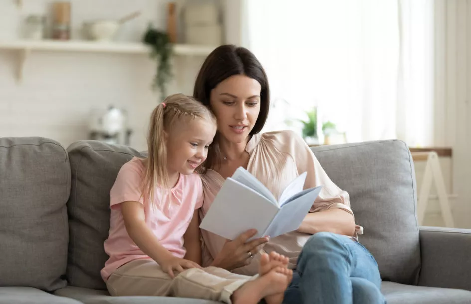 Building emotional vocabulary in preschoolers: preschool kid daughter learning story enjoying time with mum sit on couch