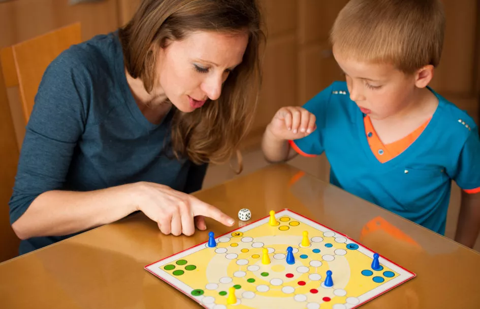 Kid and mom playing ludo game to support attention span in preschoolers