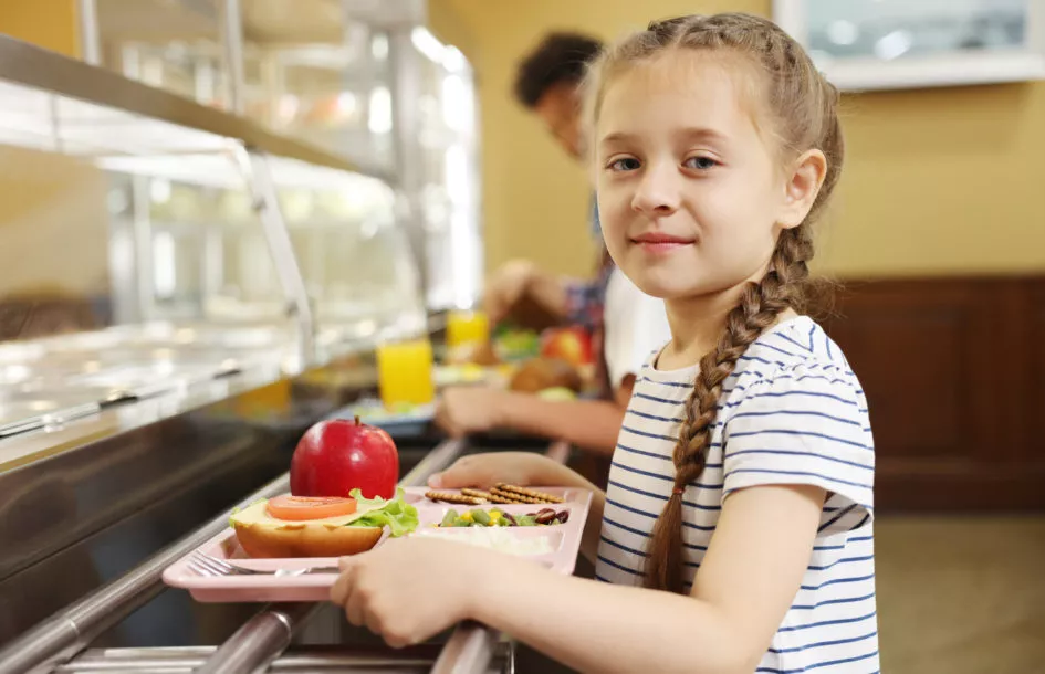 Nutrition affects learning in children: Little girl with tray of tasty food in school canteen, selective focus. Healthy meal with fruits, vegetables, and grains supporting children’s learning and focus