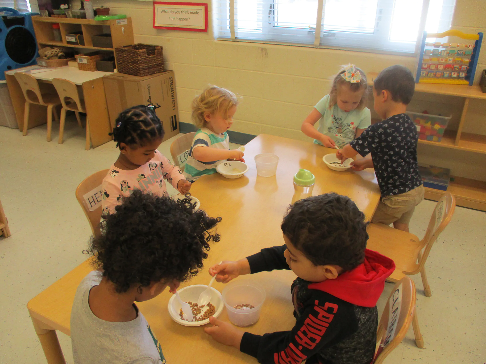 Group of preschoolers at Arcola sharing a snack at a round table, fostering community and social skills.