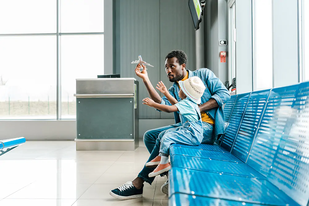 father and son sitting airport playing with toy plane