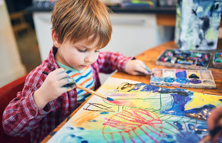 preschooler boy, painting in a sunny art studio.