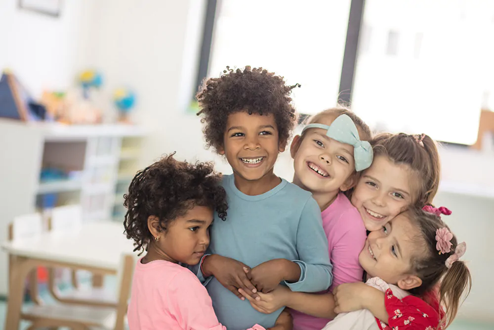 Group of happy children in childcare setting hugging