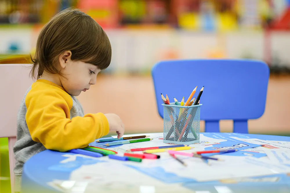 child drawing with various art supplies