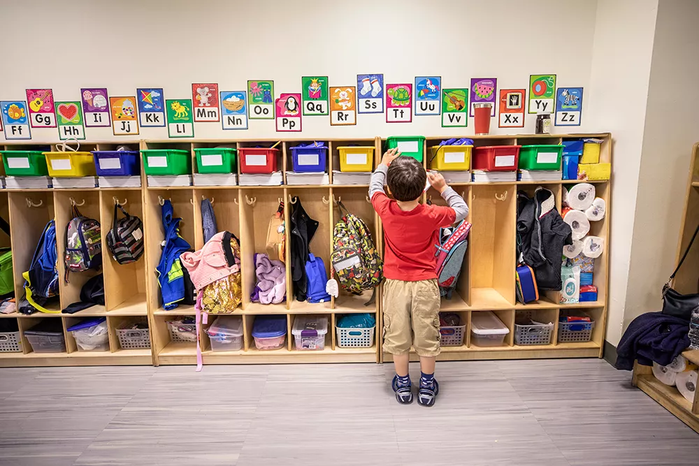preschool boy at drop off standing at his cubby