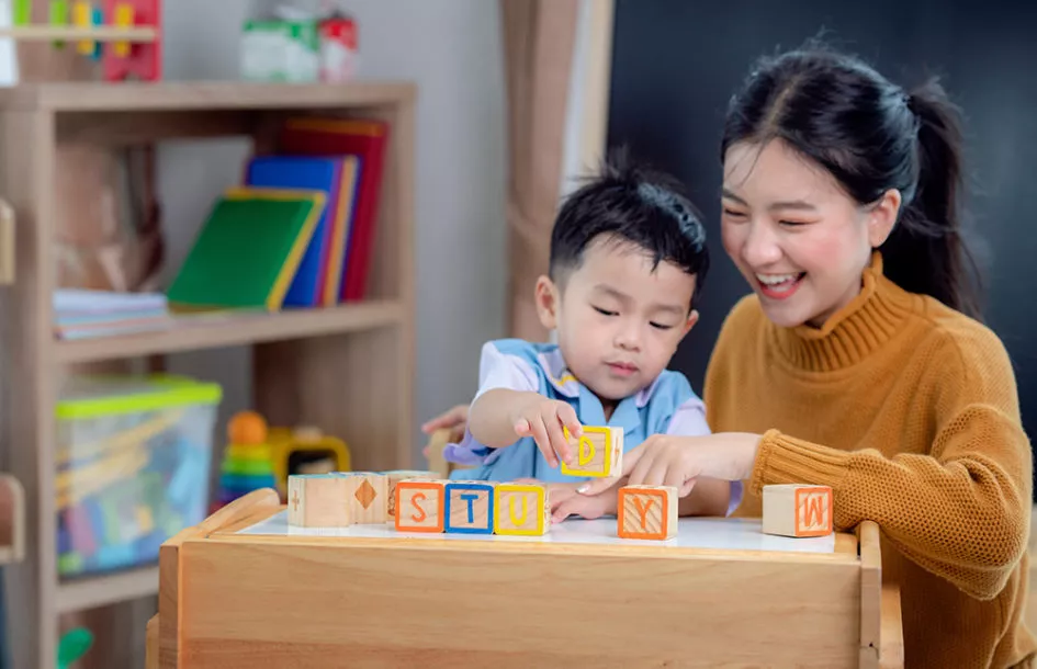 boy and teacher playing with letter blocks in preschool in maryland