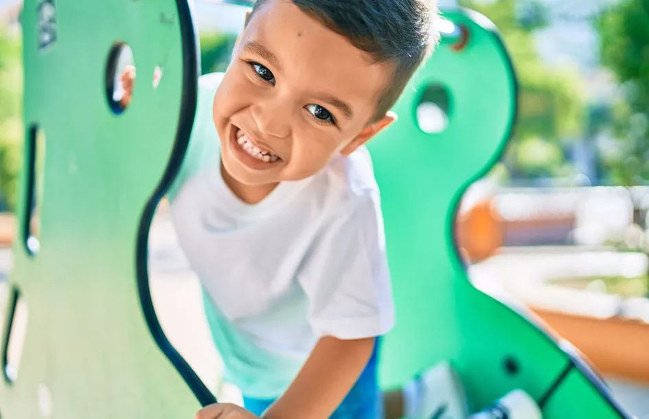 Preschool boy smiling happy playing on the playground.