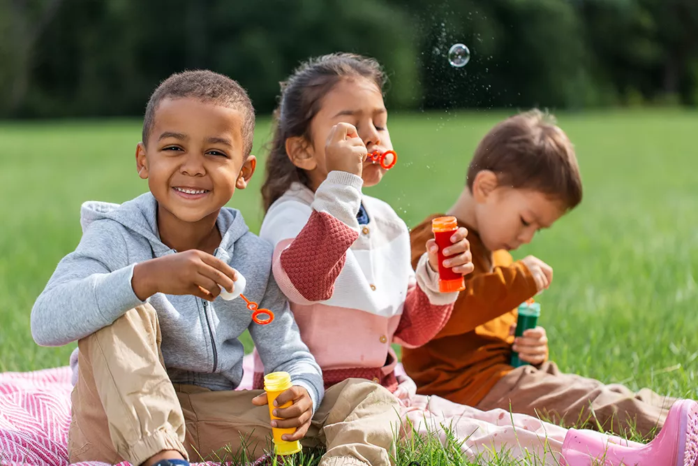 group of preschool children blowing soap bubbles