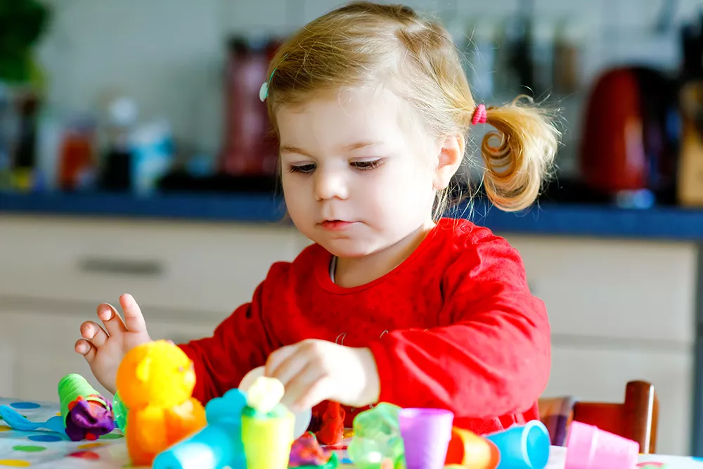 Toddler girl molding colorful modeling clay.