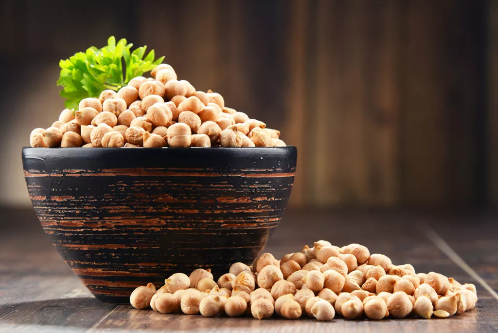 Composition with bowl of chickpeas on wooden table.