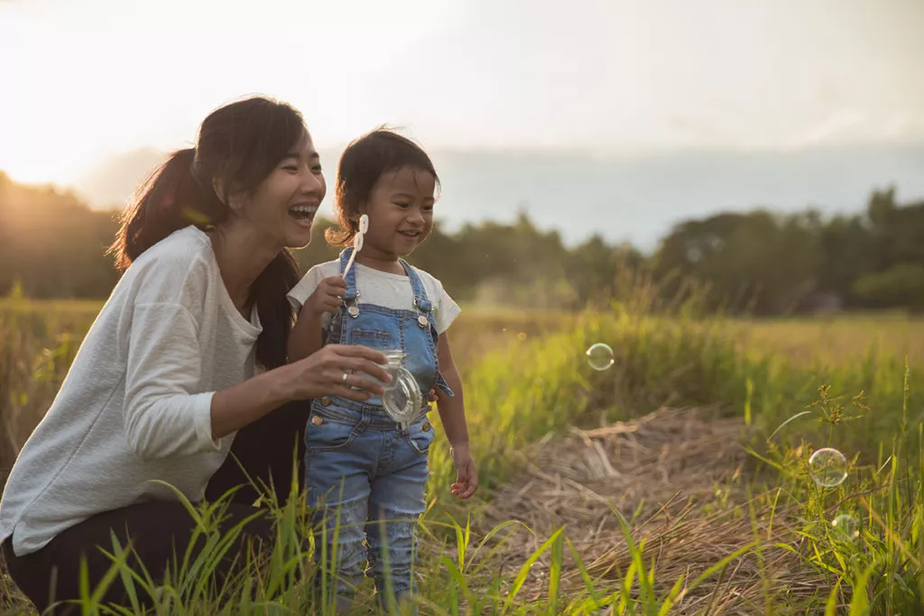 potrait of mother and daughter enjoying play with bubble outdoor in beautiful sunset