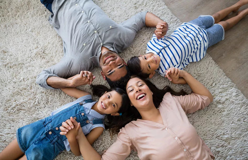 Portrait of happy parents and kids lying on rug