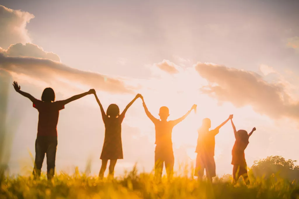 The silhouette of the children holding hands, enjoying the sunset