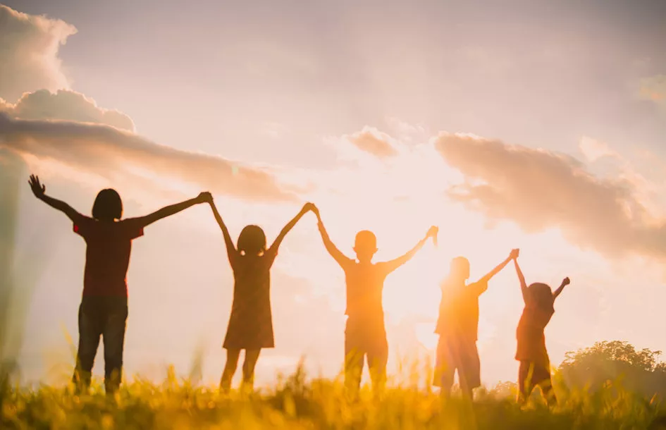 The silhouette of the children holding hands, enjoying the sunset