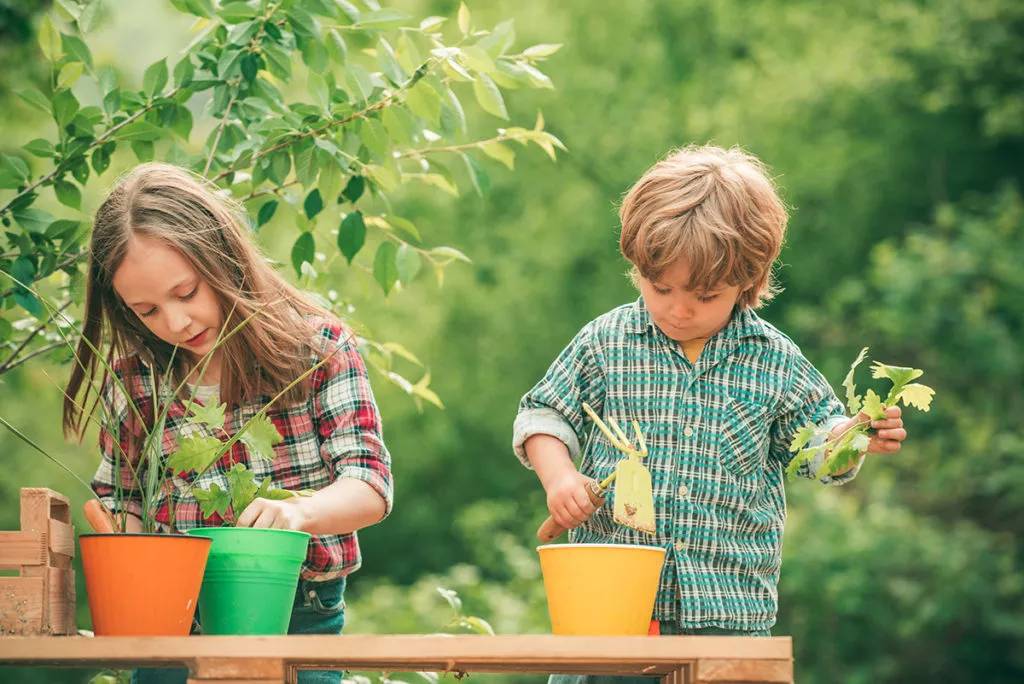 Kids planting flowers in pots.