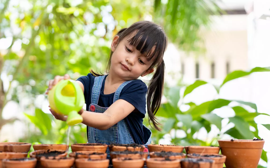 little girl watering plants in pots