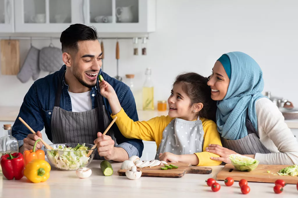little girl with her parents helping to cook in the kitchen