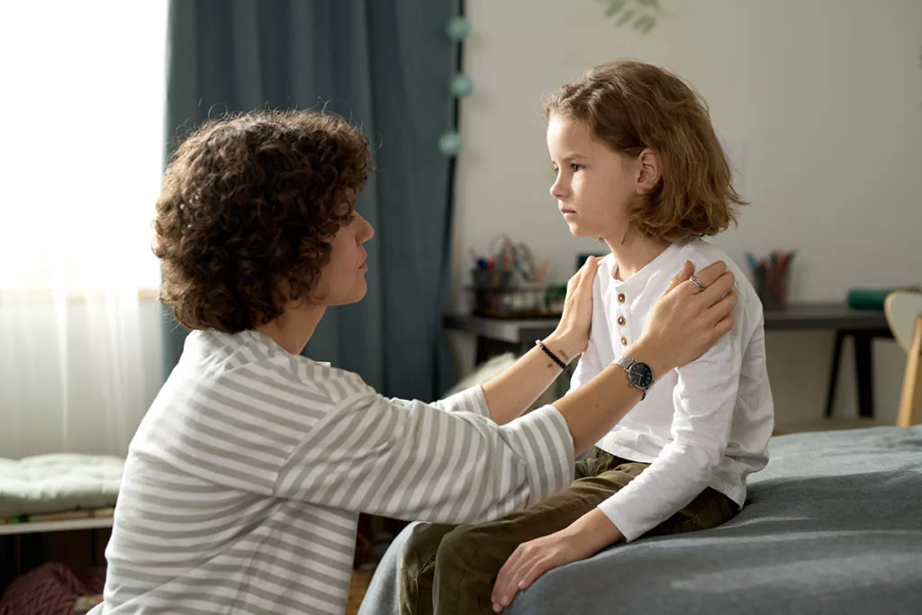 Mother sitting in front of her child and talking to him about his behavior