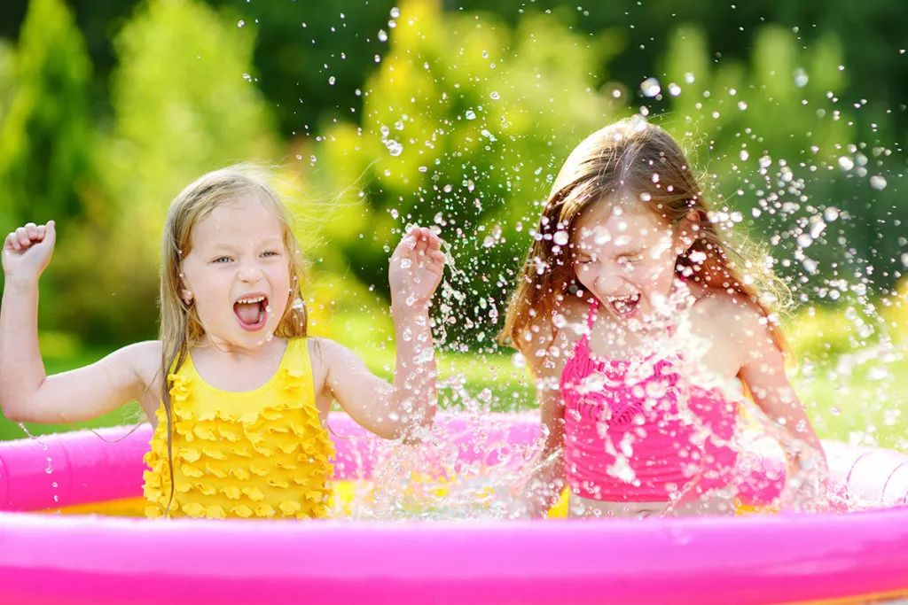 Happy children splashing in a plastic pool at a summer camp in Silver Spring, MD