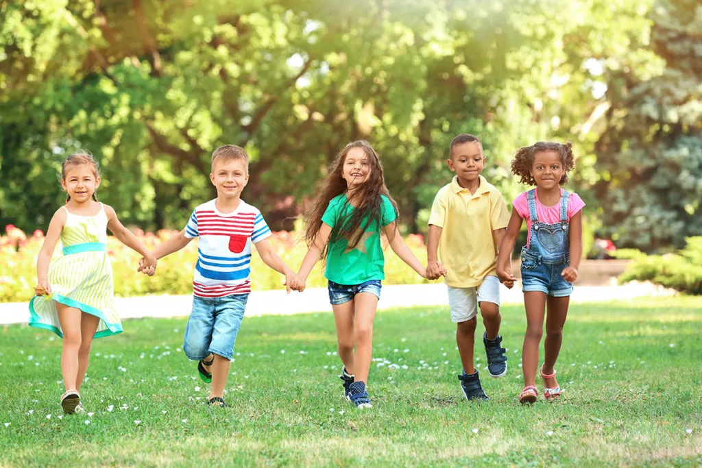 Children holding hands and playing outside while enjoying their summer at a summer camp program in Silver Spring, MD.