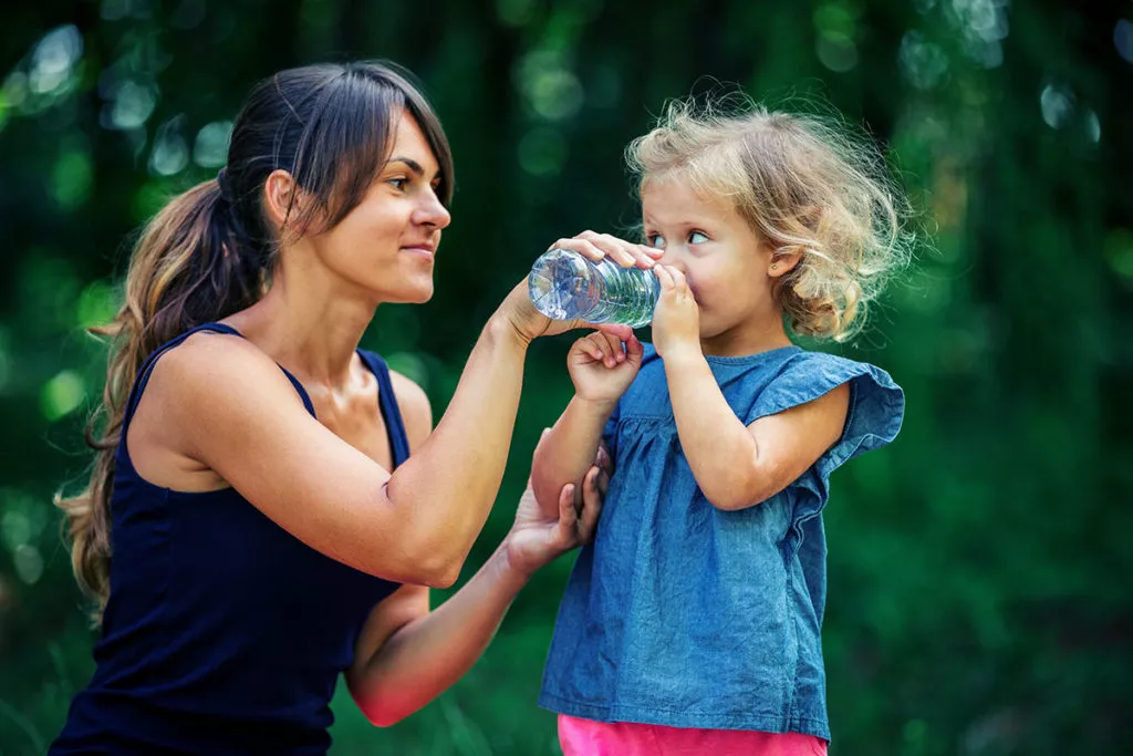 Mother giving a little girl water to drink