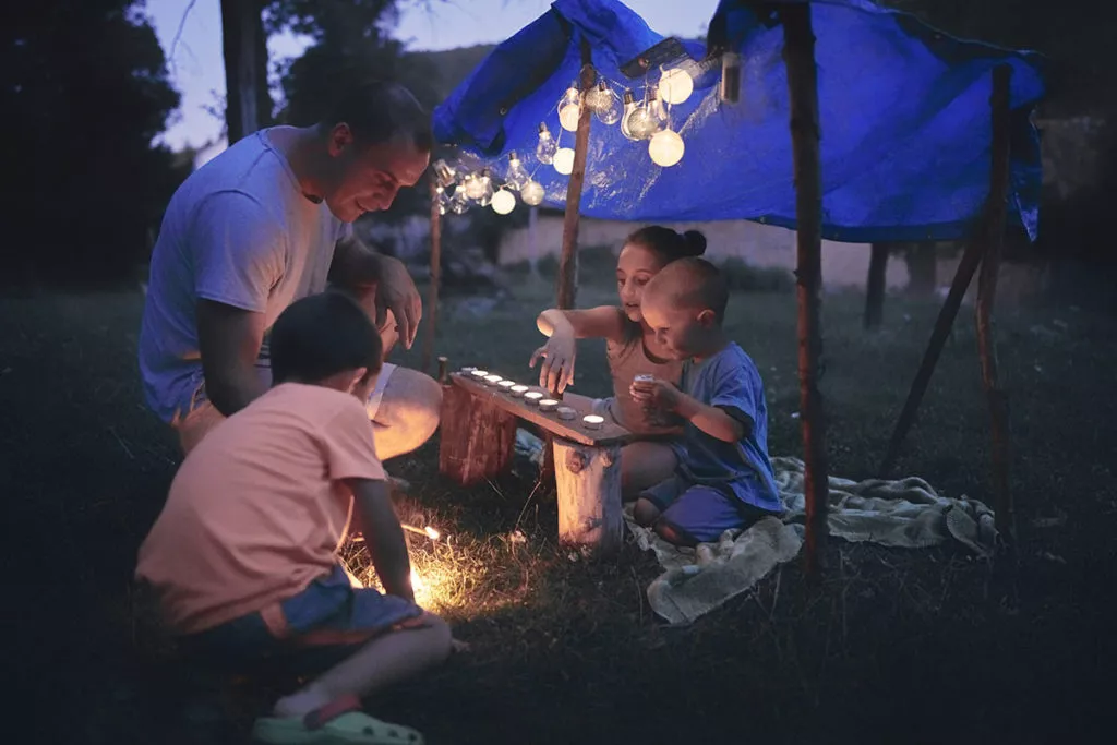 Father with children playing under their backyard tent.