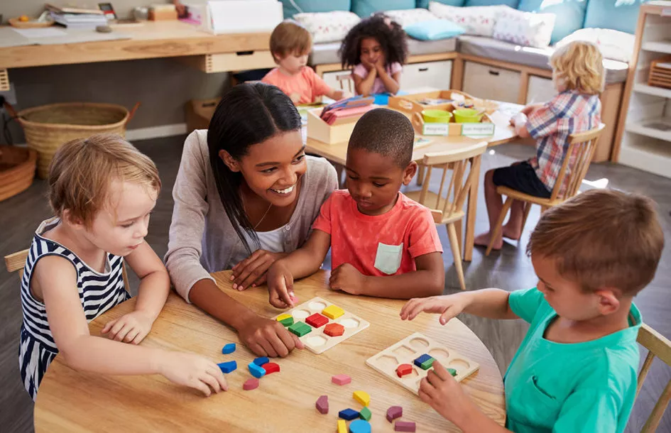 Teacher at a preschool in Silver Spring, MD helping a child with a puzzle.