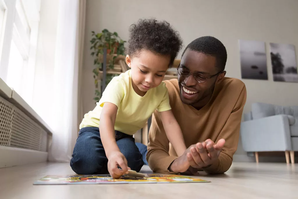 Dad and son putting together a jigsaw puzzle on the floor.