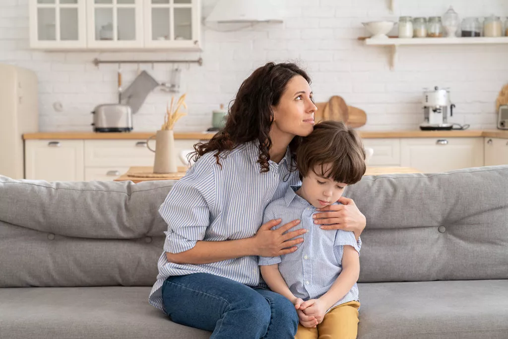 Mother sitting and comforting her son on the couch.