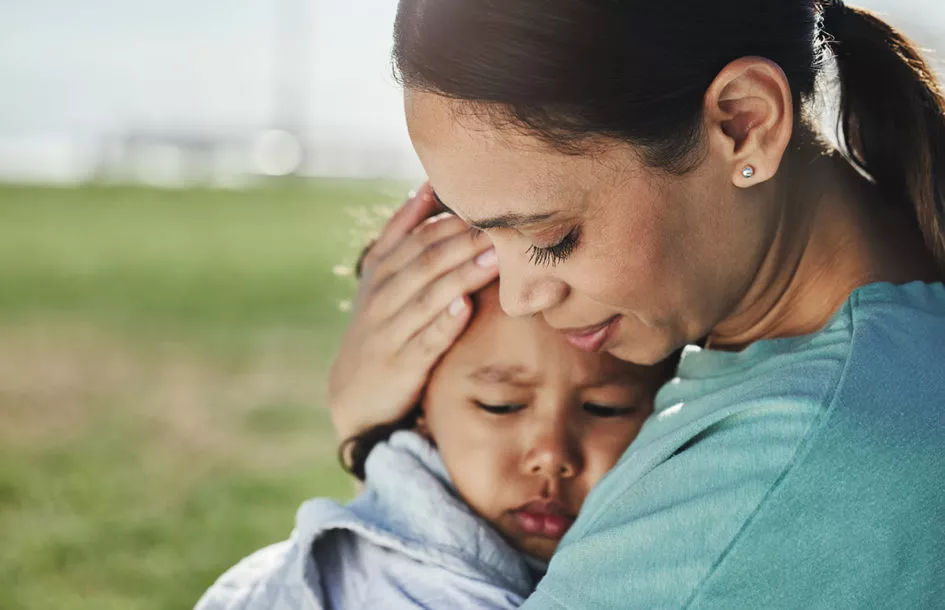 Mother comforting her preschooler in her arms.