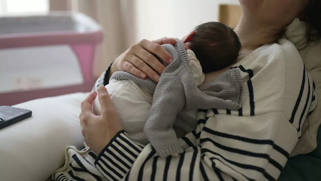 Mother holding baby on chest while taking a nap.