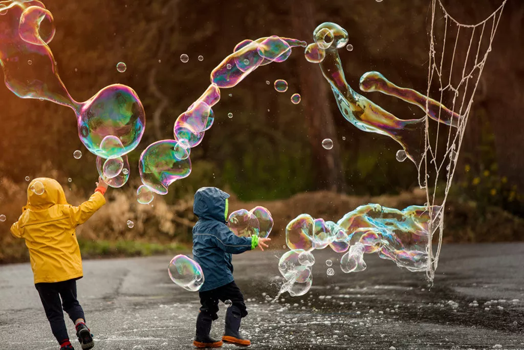 2 Preschoolers surrounded by large bubbles, having fun and learning through play.