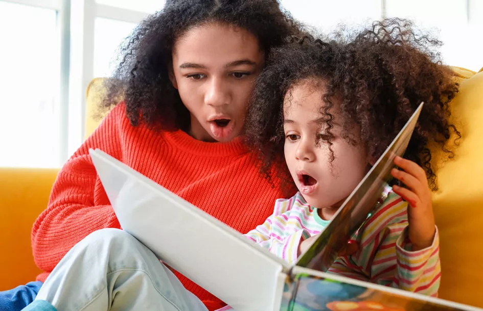 Mother with preschool daughter reading an exciting book together.