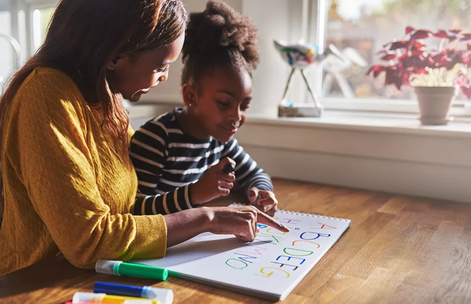 Woman and child learning alphabet to improve language skills.