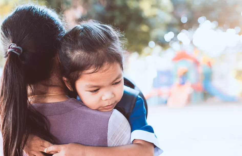 Child clinging to mom showing Separation Anxiety at preschool drop off.