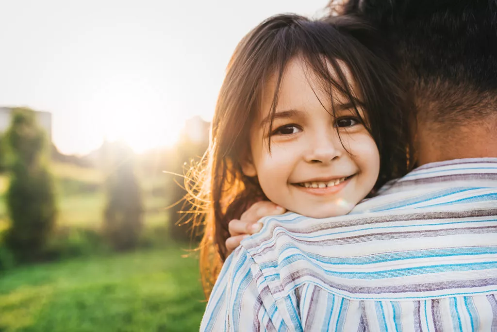 Closeup image of happy daughter embraces her dad before drop-off at preschool in Olney, MD.
