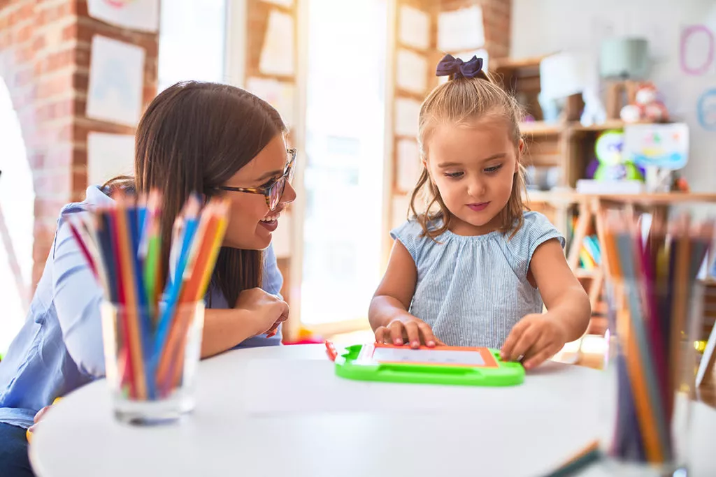 Toddler girl learning with teacher at a Rockville Child Care facility.