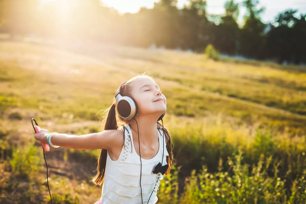 Girl listening to music with headphone and enjoying learning outside