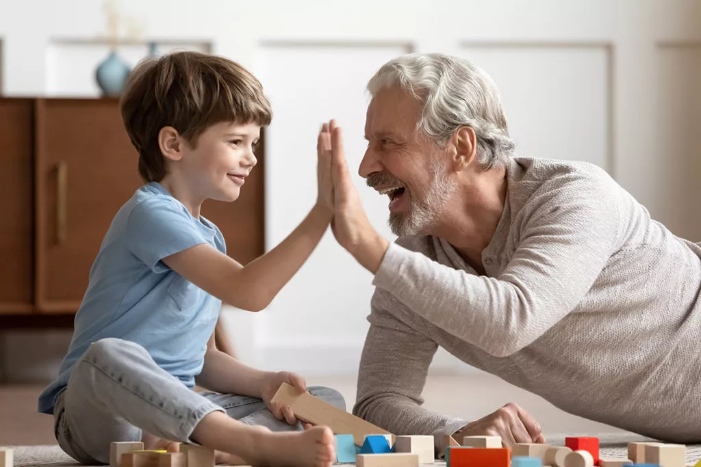 Young boy giving high five to grandfather